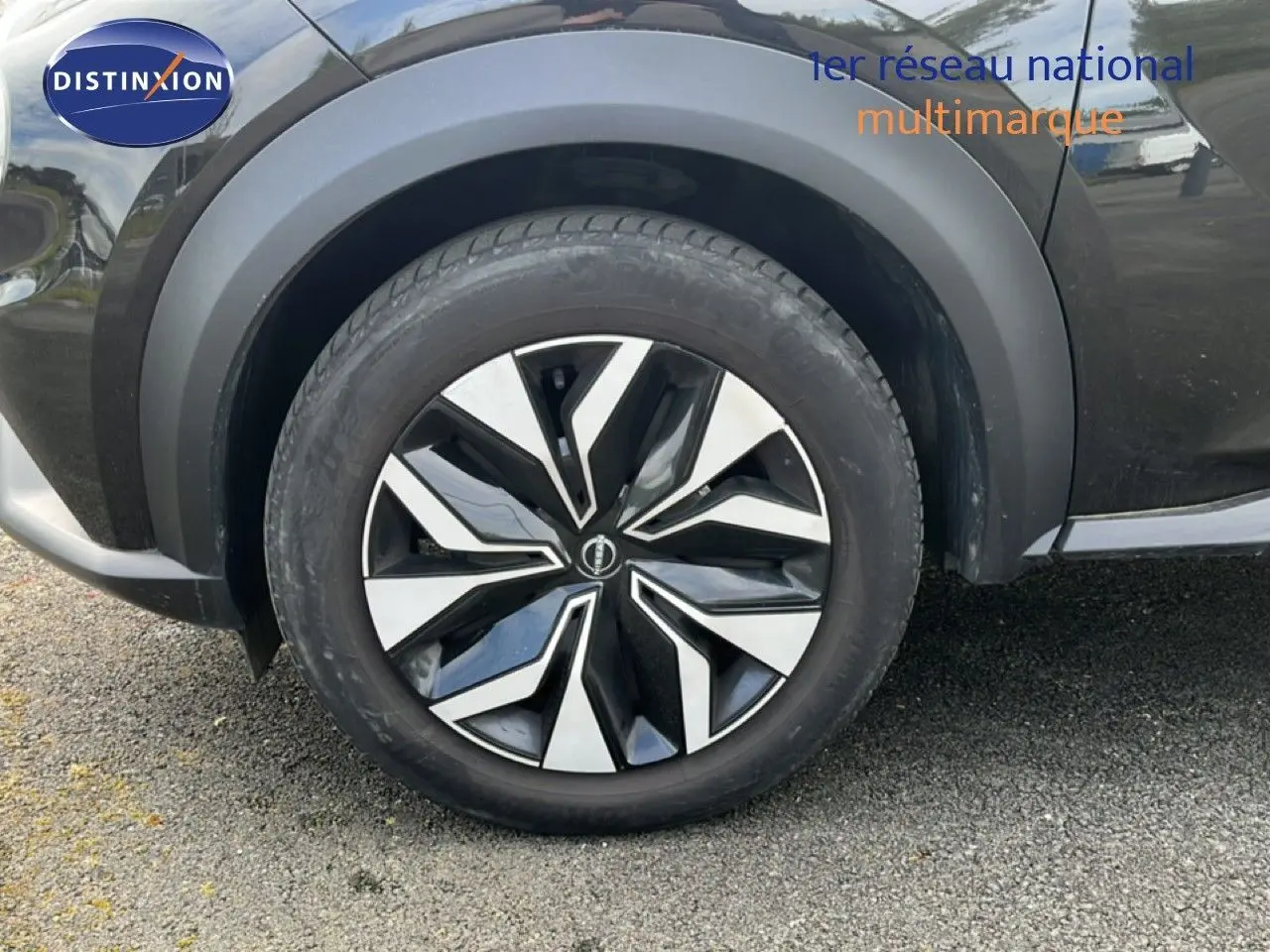 Gros plan sur la roue avant gauche du Nissan Juke noir métal 2023 avec jante alliage au design moderne.