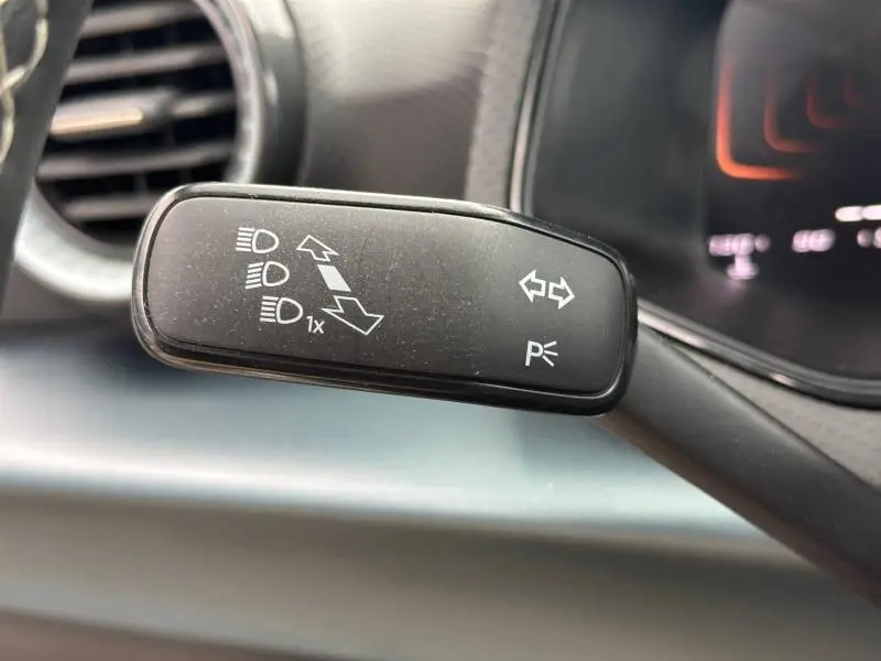 Gros plan sur la commande de clignotants noire à l'intérieur du SEAT Arona 2025, avec tableau de bord gris en arrière-plan.