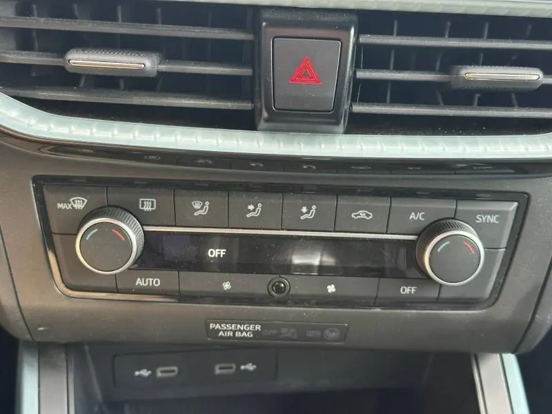 Vue rapprochée de la console centrale du SEAT Arona 2025, montrant les commandes de climatisation bi-zone avec boutons rotatifs.