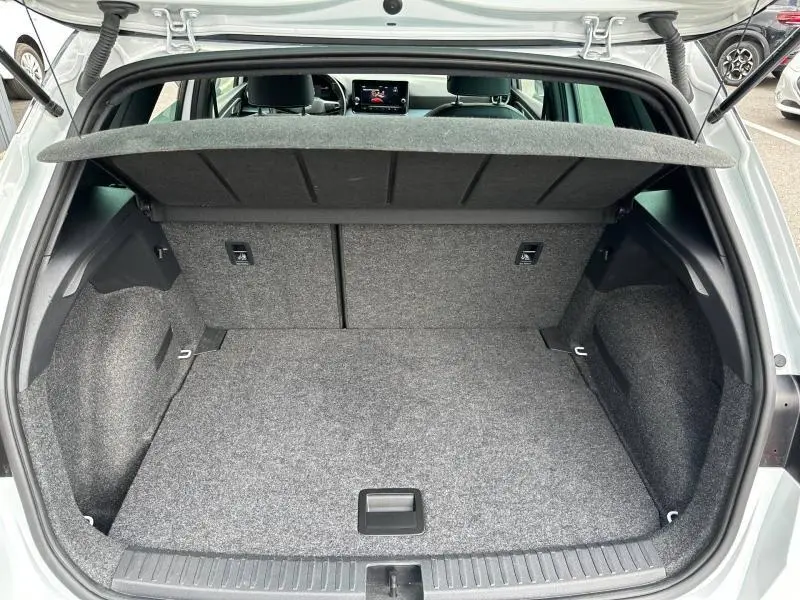 Coffre ouvert vu de l'arrière d'un SEAT Arona blanc Nevada avec cache-bagages et intérieur gris.