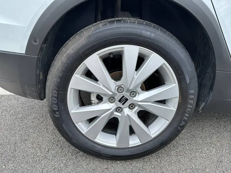 Gros plan sur la roue avant gauche de la SEAT Arona blanche avec jante alu à 10 branches et logo central noir.