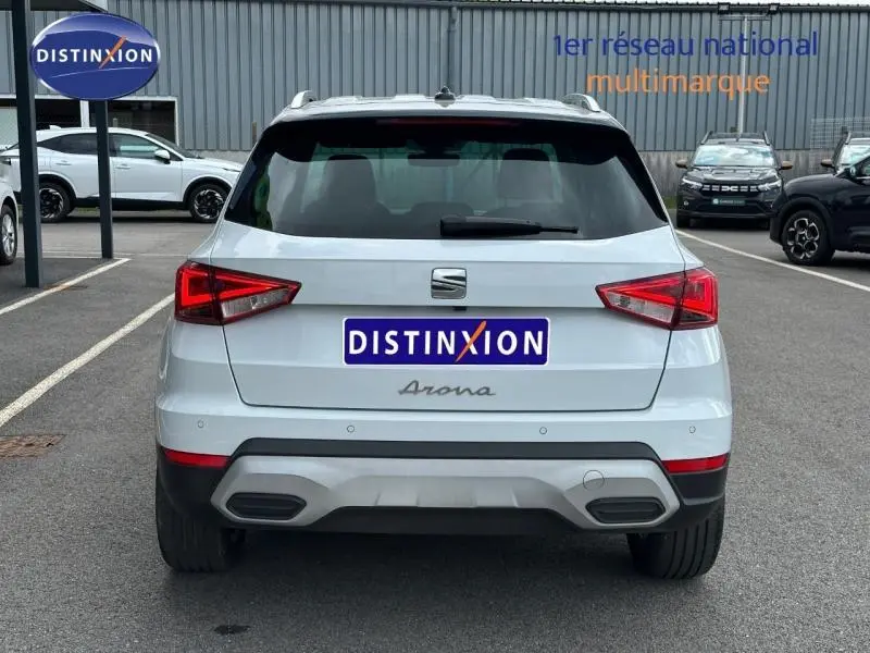 Vue arrière d'un SEAT Arona blanc Nevada avec toit noir, stationné sur un parking extérieur.