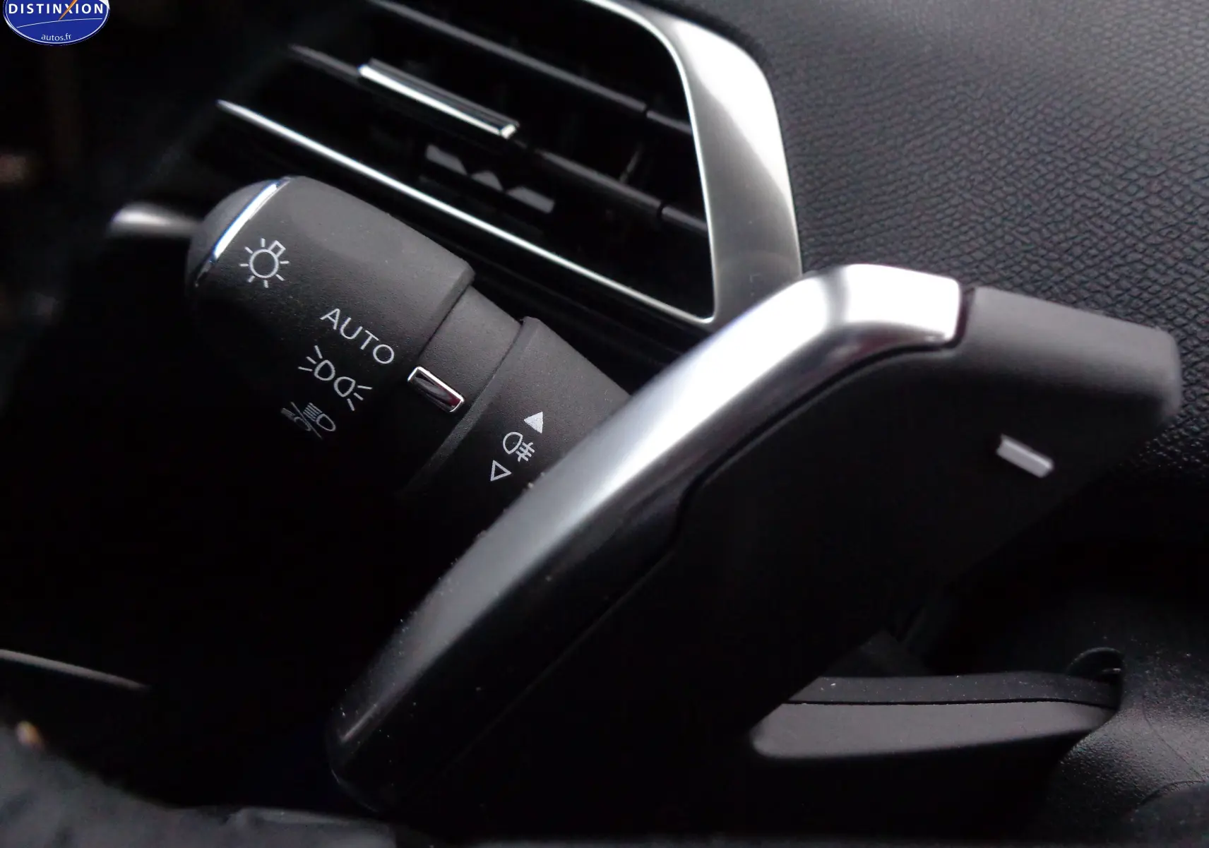 Gros plan sur la commande des phares et clignotants à gauche du volant dans l'habitacle noir du Peugeot 3008 gris Artense.