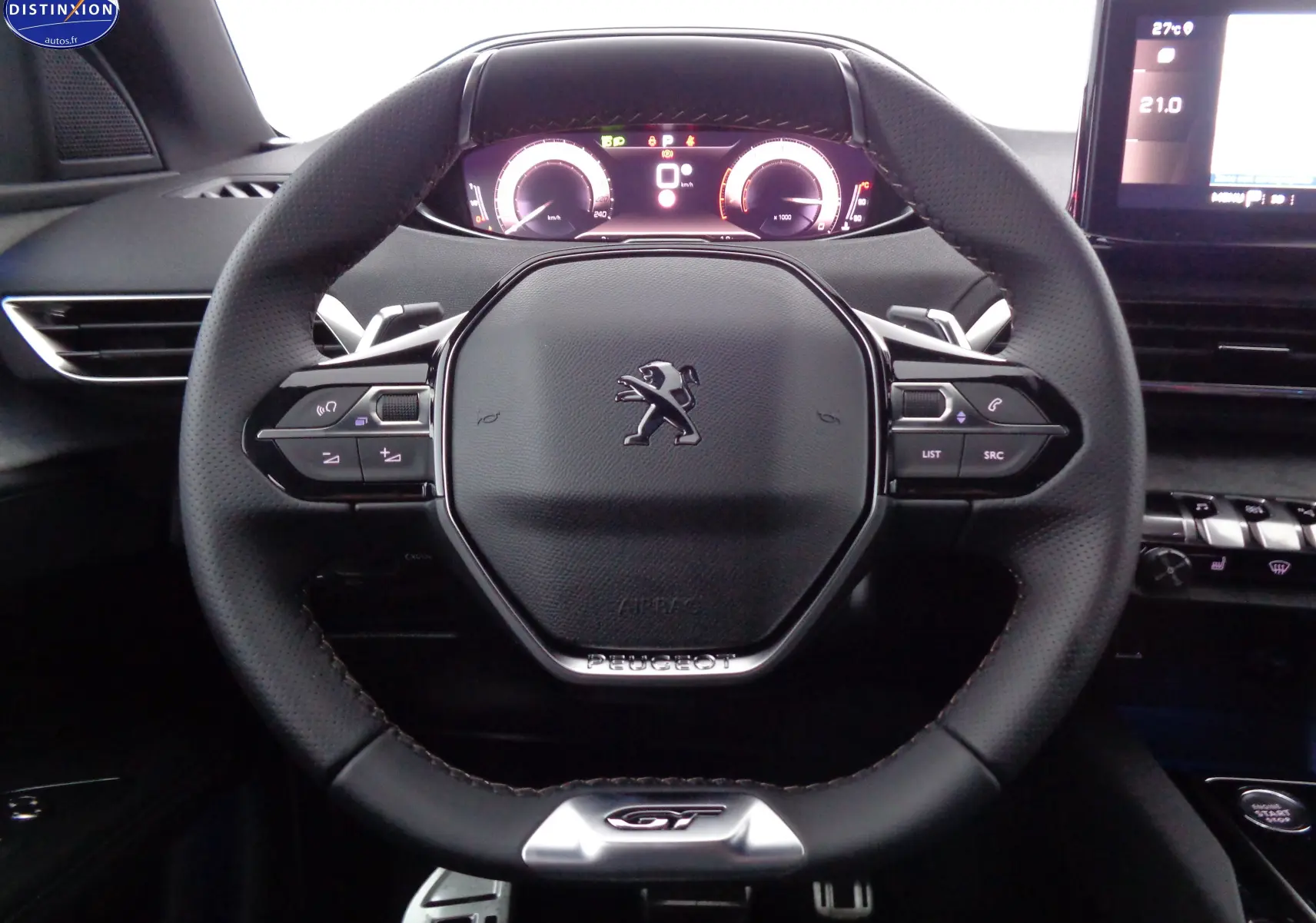 Volant en cuir noir avec logo Peugeot et badge GT, tableau de bord digital et écran tactile visibles dans un Peugeot 3008 gris 2023.
