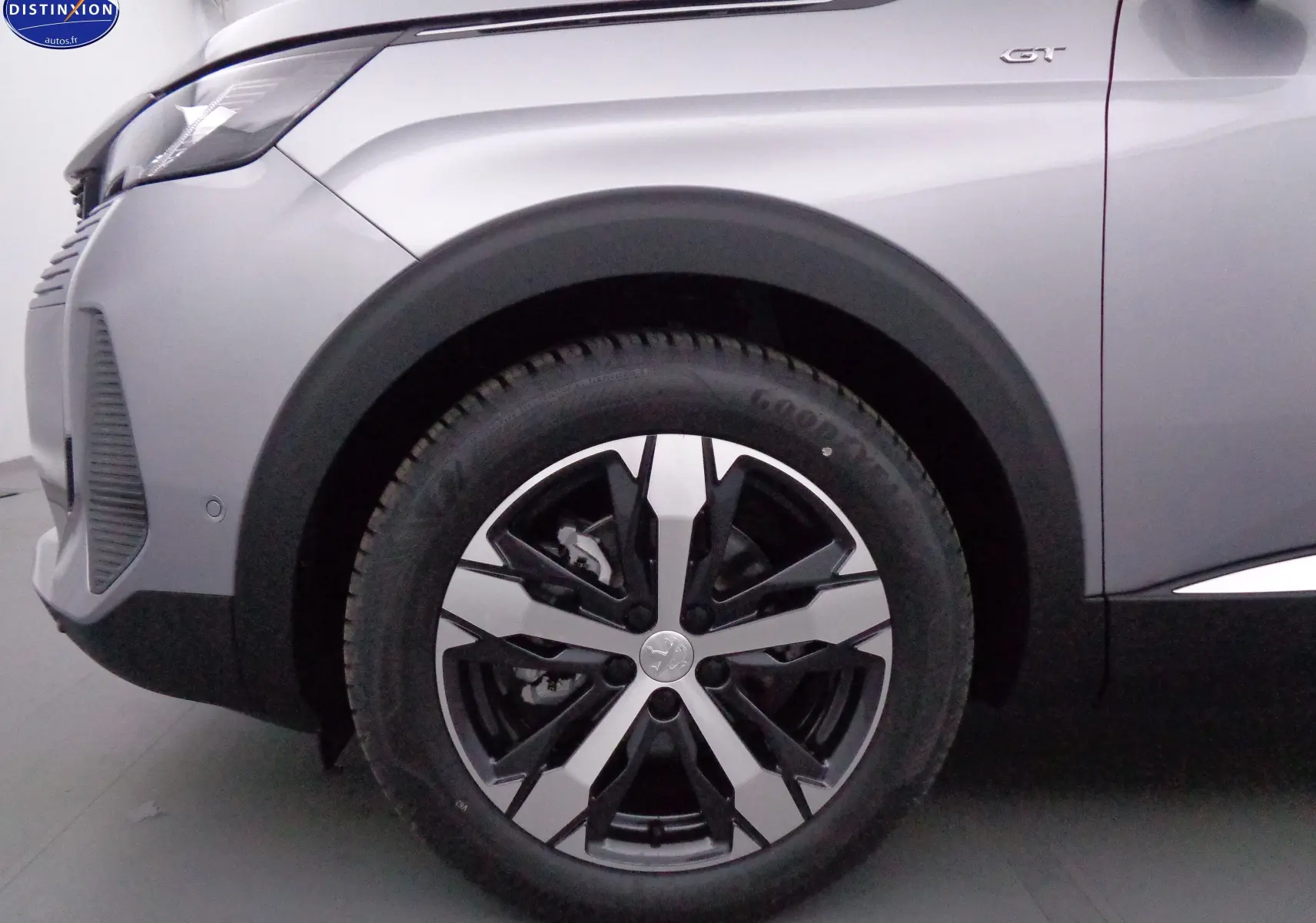 Gros plan sur la roue avant gauche et l'aile gris artense métallisé du Peugeot 3008 GT 2023 avec logo GT visible.