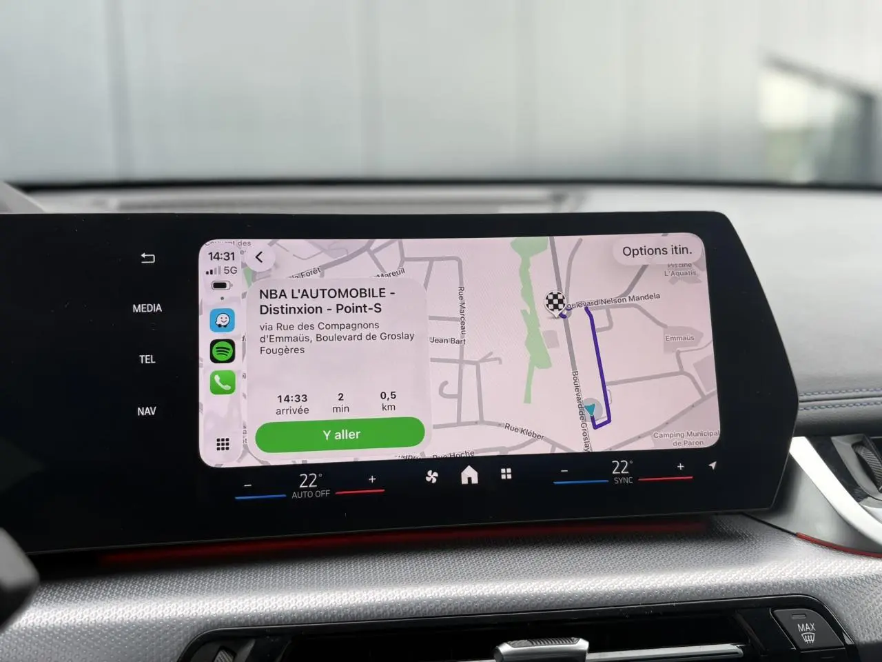Écran tactile incurvé du tableau de bord du BMW X1 blanc Mineral, affichant la navigation GPS en cours.