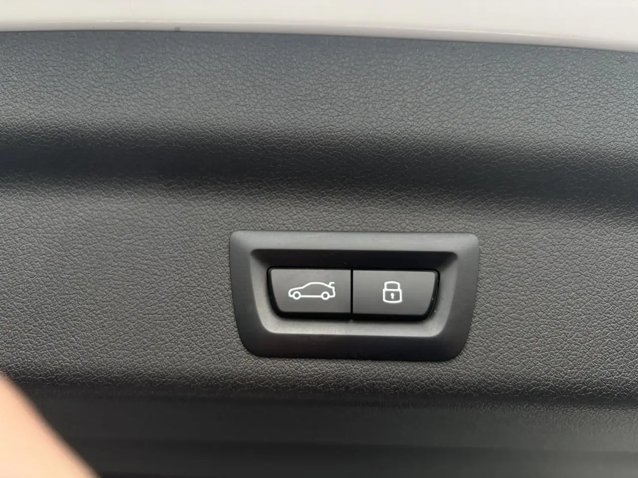 Gros plan sur les boutons d'ouverture et de verrouillage du hayon intérieur d'un BMW X1 blanc Mineral.