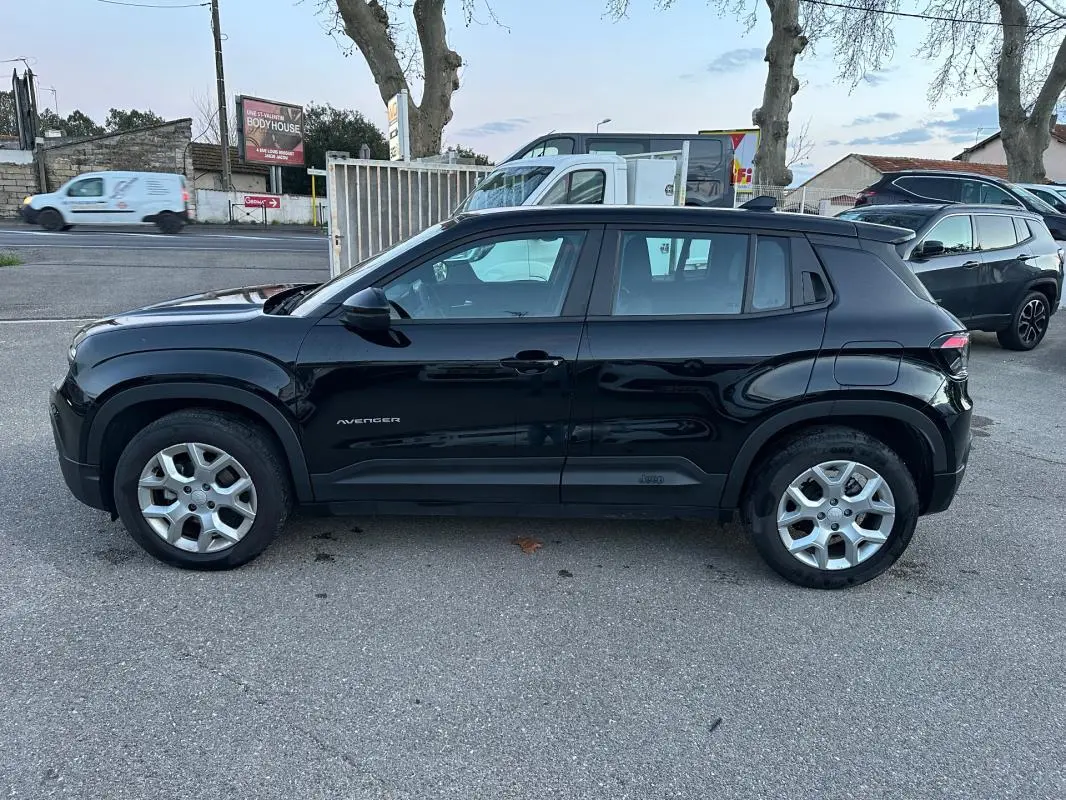 Vue de profil côté gauche d'un Jeep Avenger noir 2025 avec jantes alliage 17 pouces sur un parking extérieur.