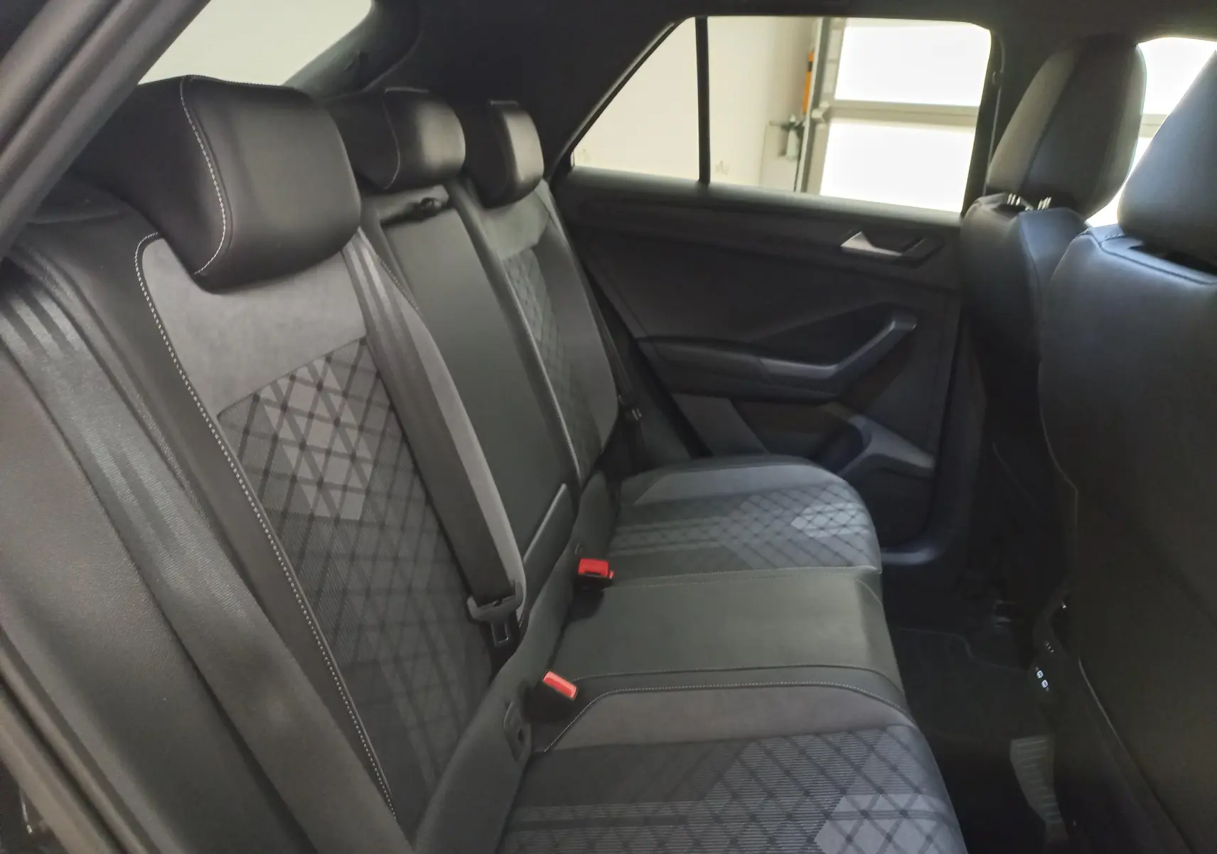 Vue intérieure côté droit des sièges arrière noirs avec surpiqûres et motifs géométriques du Volkswagen T-Roc 1.5 TSI 2025.