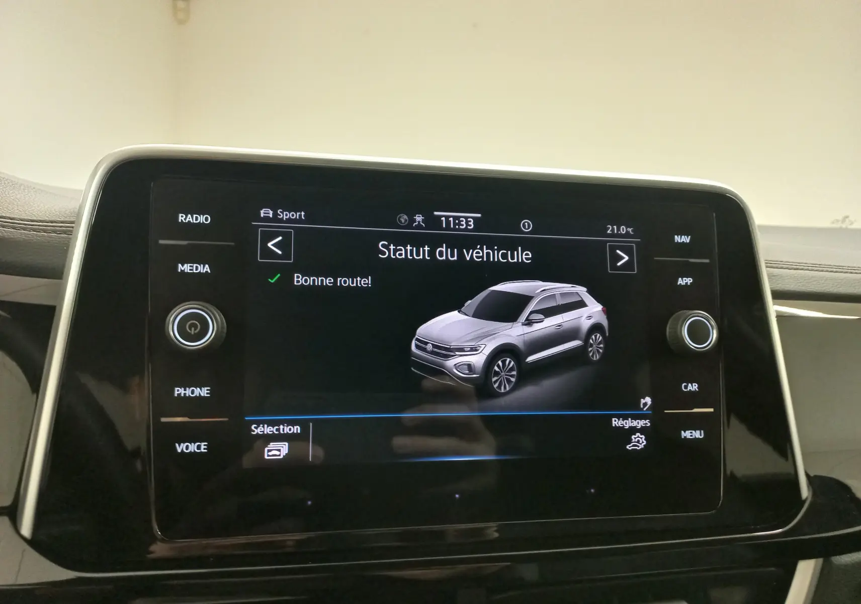 Écran tactile intérieur affichant le statut d’un Volkswagen T-Roc 2025 en vue 3/4 avant grise sur fond noir.