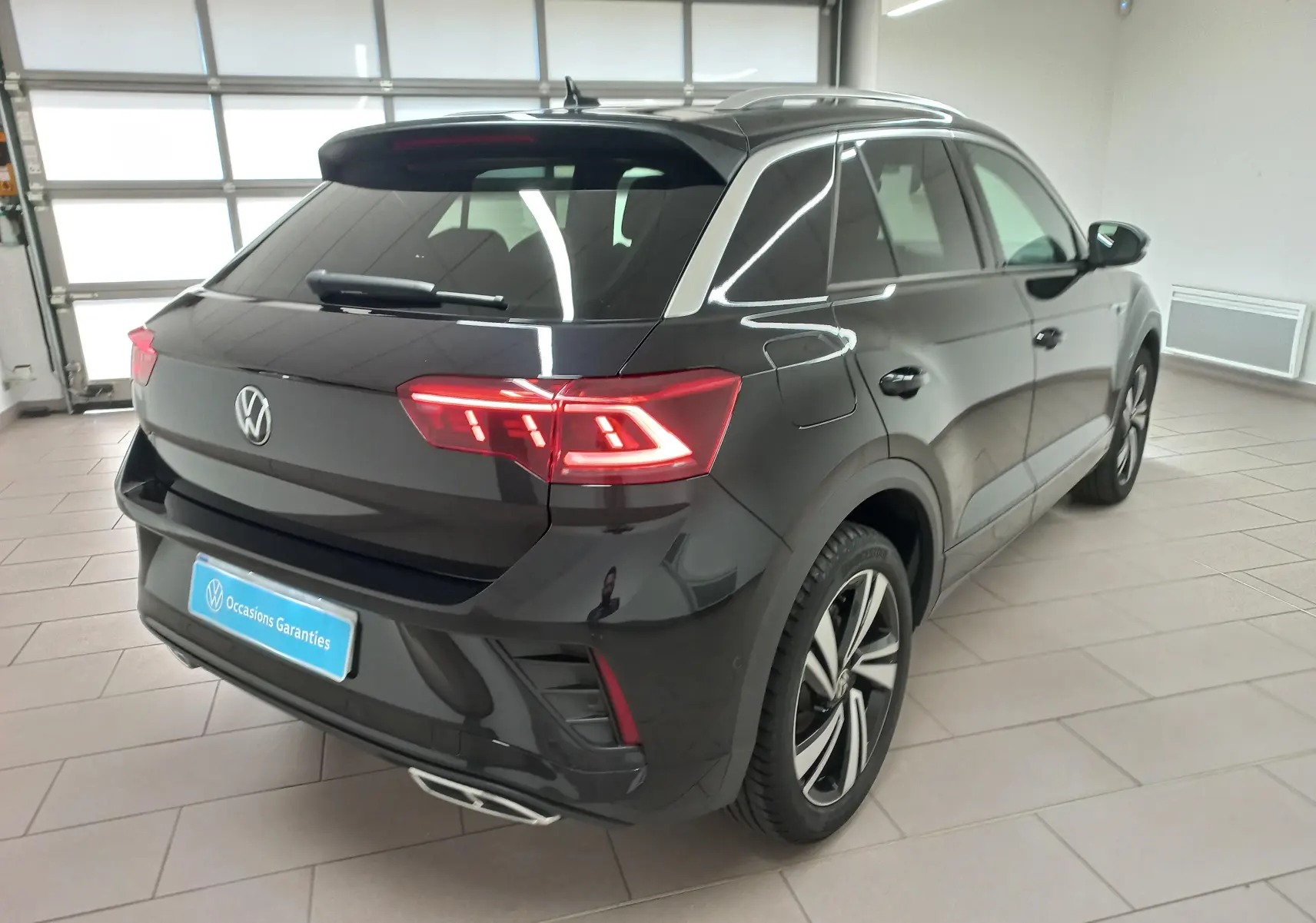 Volkswagen T-Roc noir intense nacré vu en 3/4 arrière droit, avec feux LED et jantes R-Line distinctives.