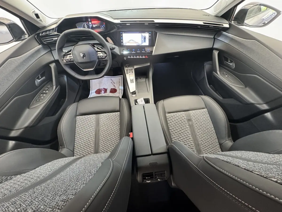 Vue intérieure avant de la Peugeot 308 2026 avec volant cuir multifonctions et écran tactile central.