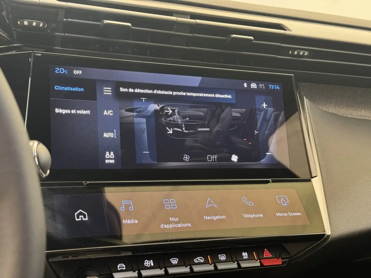 Écran tactile central de la Peugeot 308 gris clair, affichant les réglages climatisation et sièges, vue intérieure frontale.