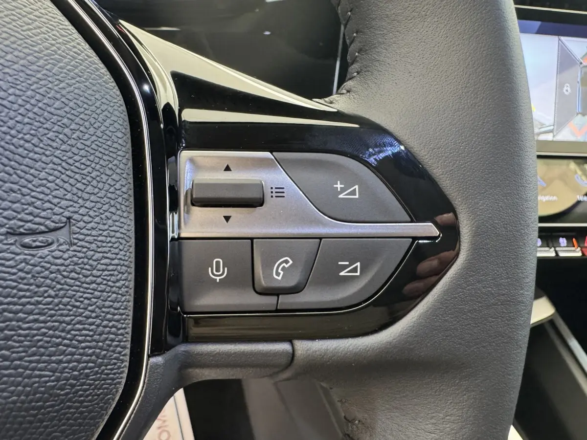 Gros plan sur le volant cuir multifonctions côté gauche de la Peugeot 308 gris clair avec commandes vocales et téléphone.