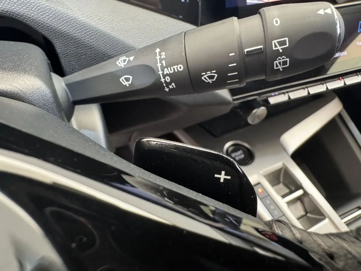 Gros plan sur la commande de lève-glace et palette de changement de vitesse côté gauche dans l’habitacle gris du Peugeot 308 2026.