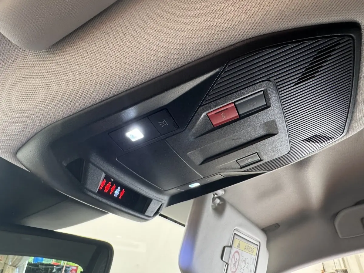 Vue en contre-plongée du plafonnier noir avec boutons SOS et éclairage intérieur de la Peugeot 308 gris clair.