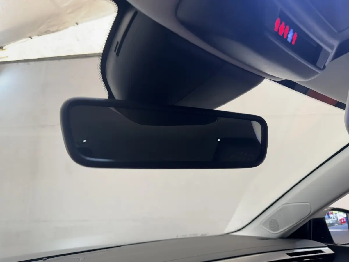 Vue intérieure centrée sur le rétroviseur intérieur d'une Peugeot 308 gris clair, avec pare-brise et partie du tableau de bord visibles.