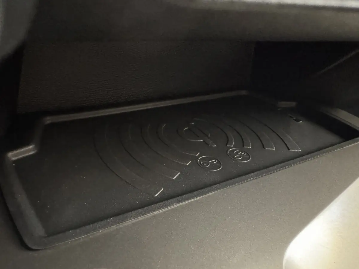 Gros plan sur le tapis de recharge sans fil noir dans la boîte à gants de la Peugeot 308 gris clair 2026.