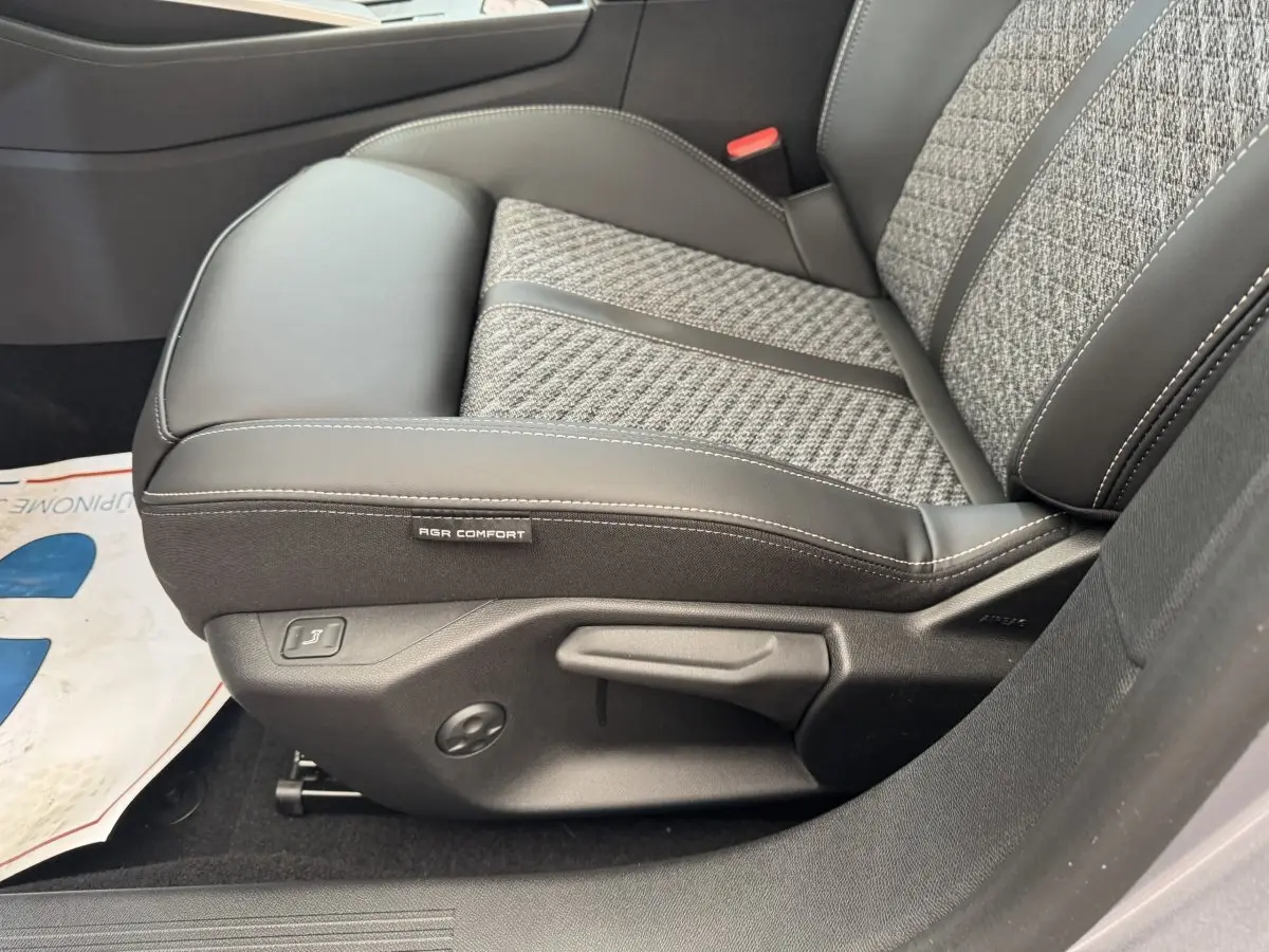 Gros plan sur le siège avant droit gris clair de la Peugeot 308 2026 avec étiquette AGR Comfort et commandes de réglage.