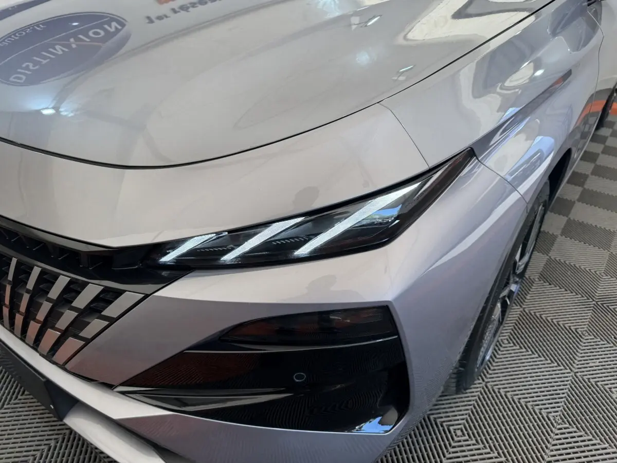 Gros plan sur l'avant droit gris clair du Peugeot 308 2026, mettant en valeur ses phares LED et sa calandre distinctive.