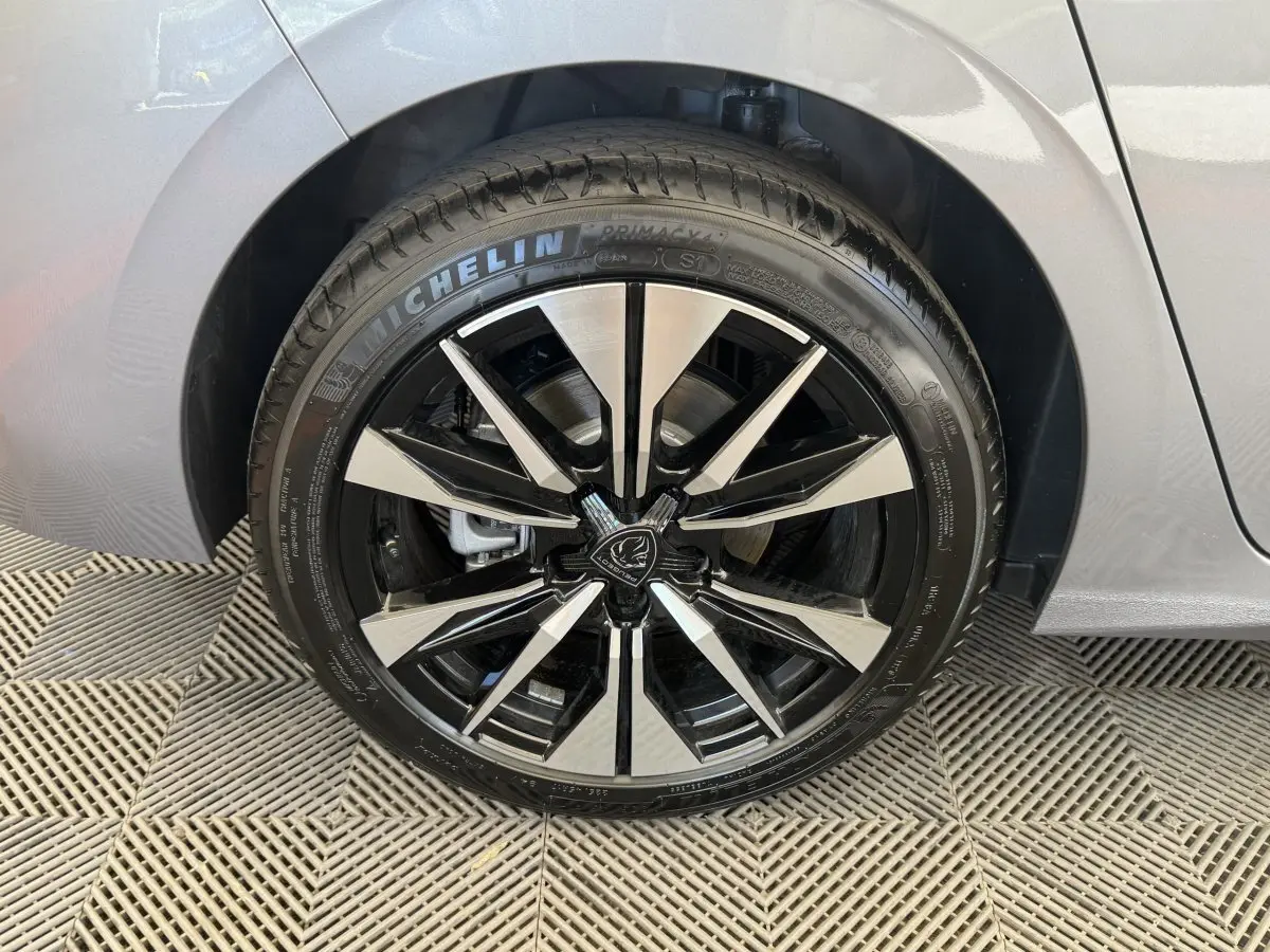 Gros plan sur la roue avant droite d’une Peugeot 308 gris clair, jante alliage noire et argentée design moderne.