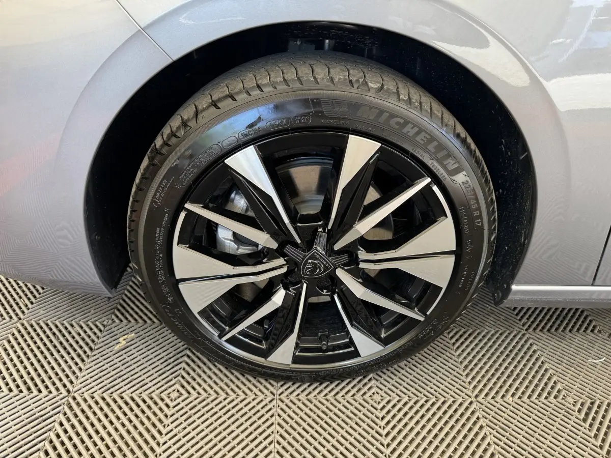 Gros plan sur la roue avant gauche de la Peugeot 308 gris clair, jante alliage noire et argentée au design moderne.