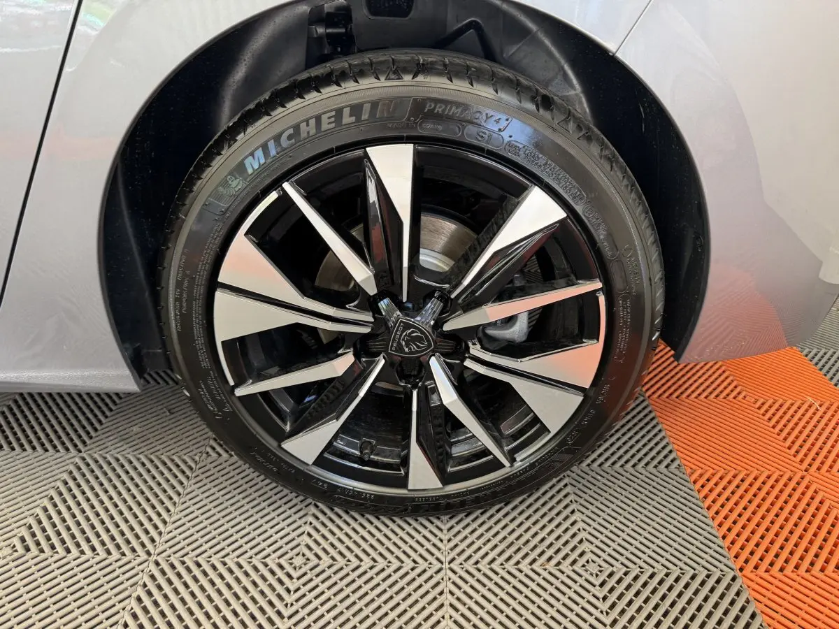 Gros plan sur la roue avant droite gris clair de la Peugeot 308 avec jante alliage noire et argentée distinctive.