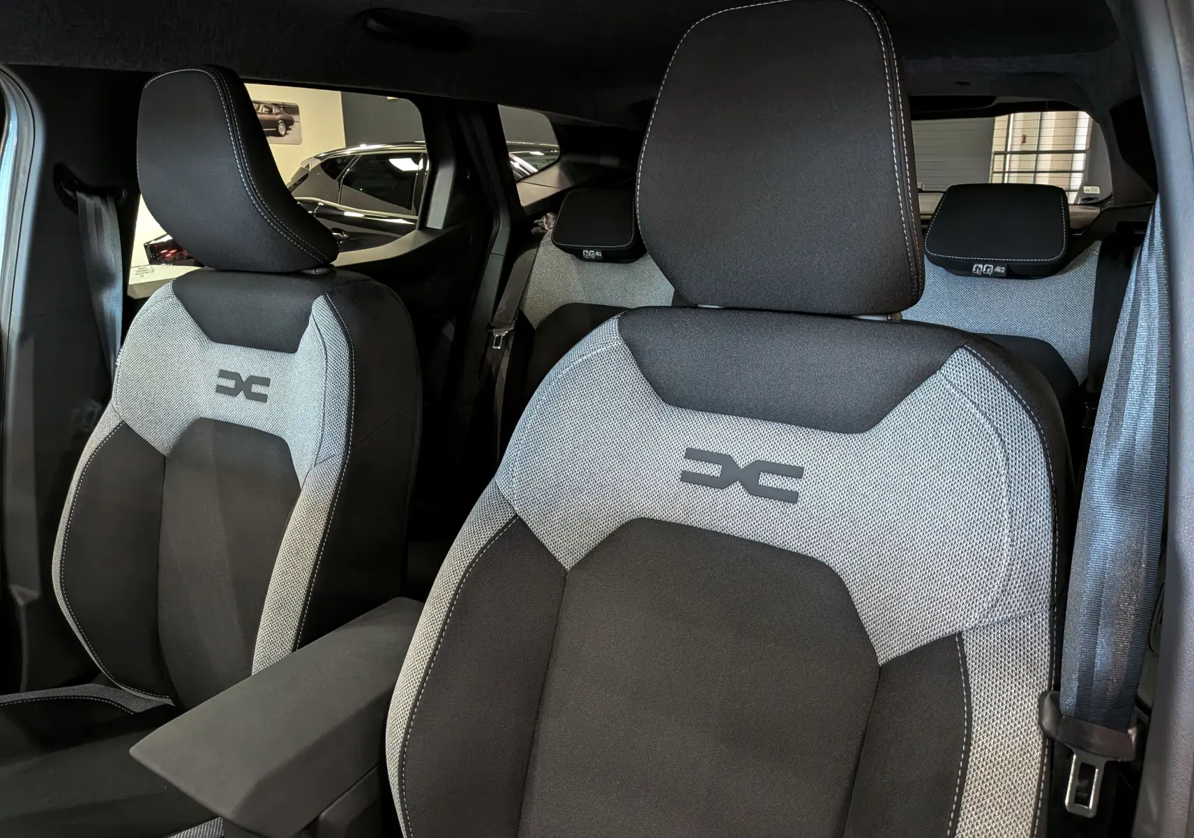 Vue intérieure rapprochée des sièges avant gris et noir avec logo Dacia sur un Duster Hybrid-G 2026.