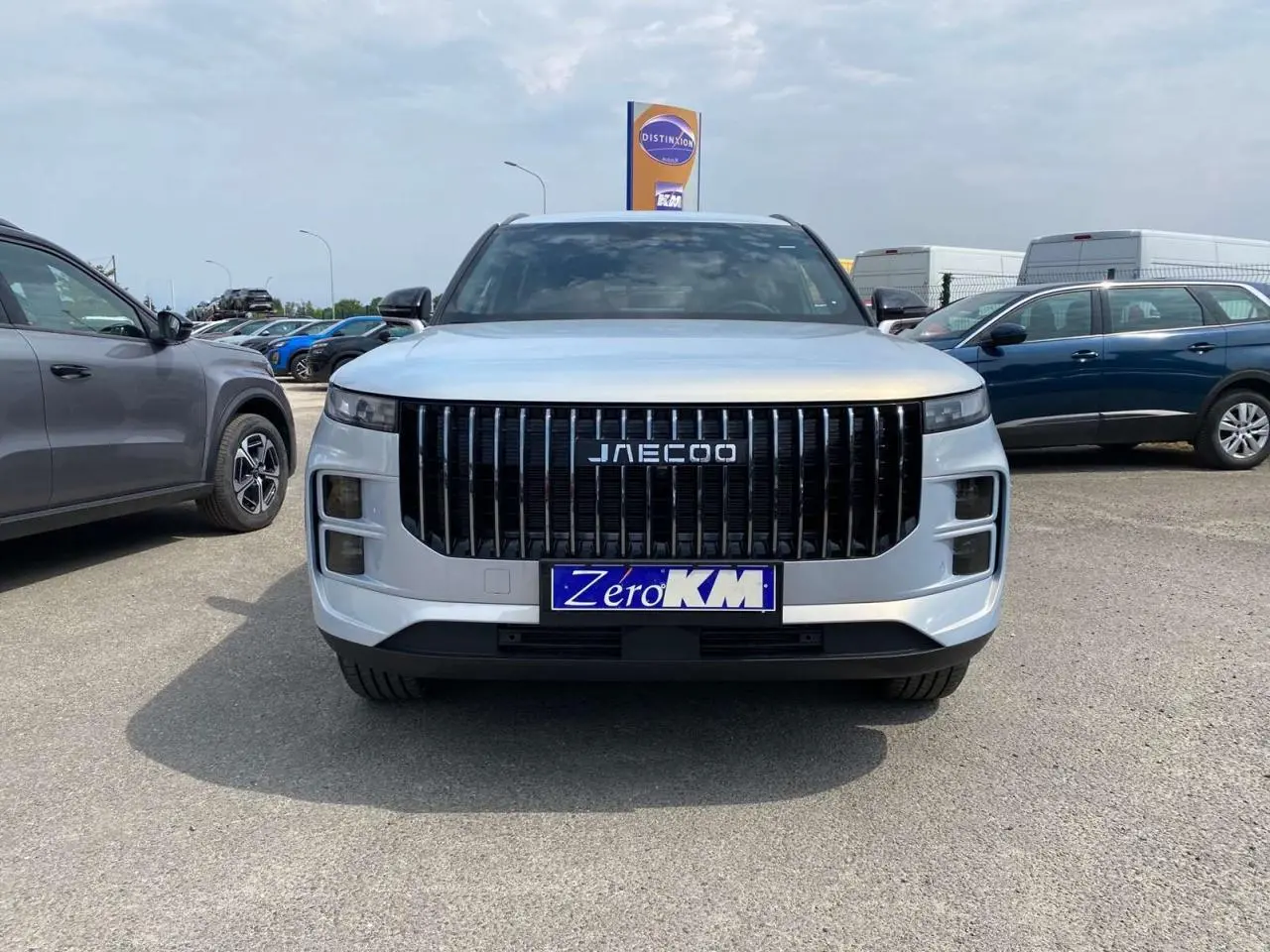 Vue frontale d'un JAECOO J7 1.5 SHS-P argent Moonlight avec calandre verticale noire et plaque Zero KM.