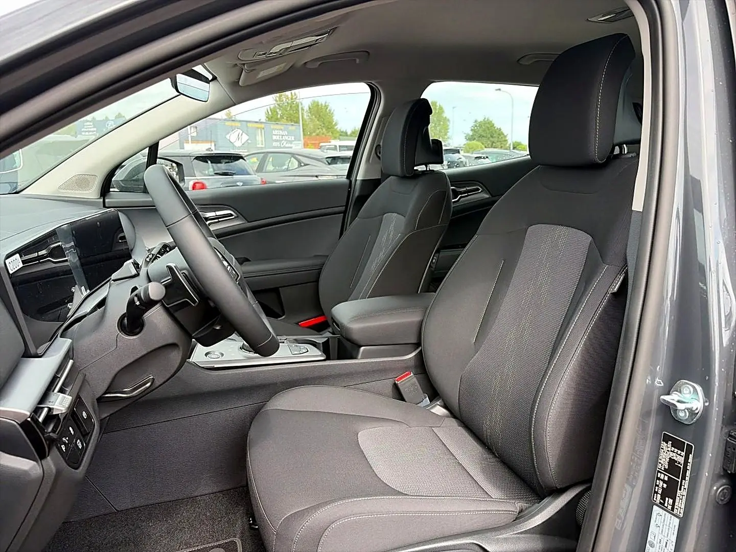 Vue intérieure côté conducteur du Kia Sportage gris eclipse 2026, montrant sièges et volant cuir multifonction.