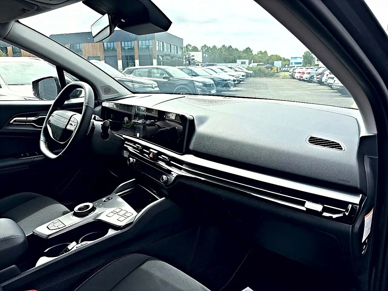 Vue intérieure côté conducteur du Kia Sportage 1.6 hybride gris eclipse, avec tableau de bord moderne et écran tactile large.