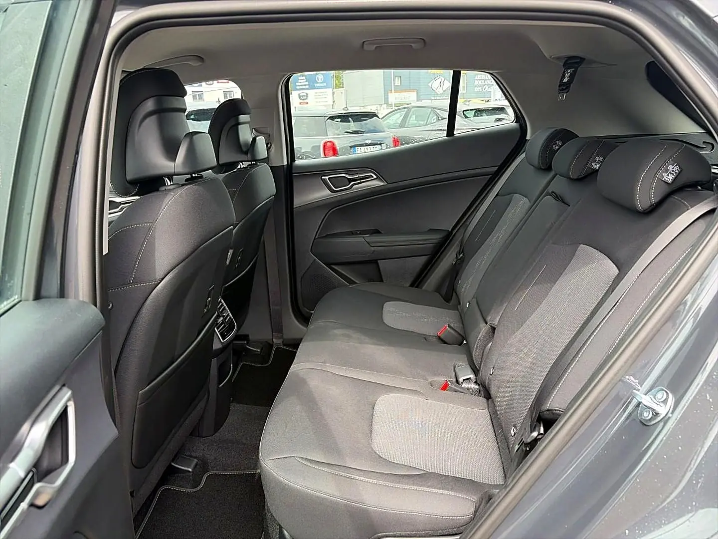 Vue intérieure côté droit montrant la banquette arrière grise eclipse du Kia Sportage 1.6 hybride 2026 avec appuie-têtes réglables.