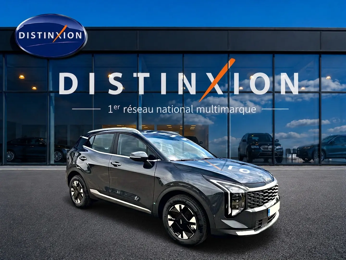 KIA SPORTAGE 1.6 hybride gris eclipse en 3/4 avant droit, avec jantes alu et calandre distinctive devant showroom Distinxion.