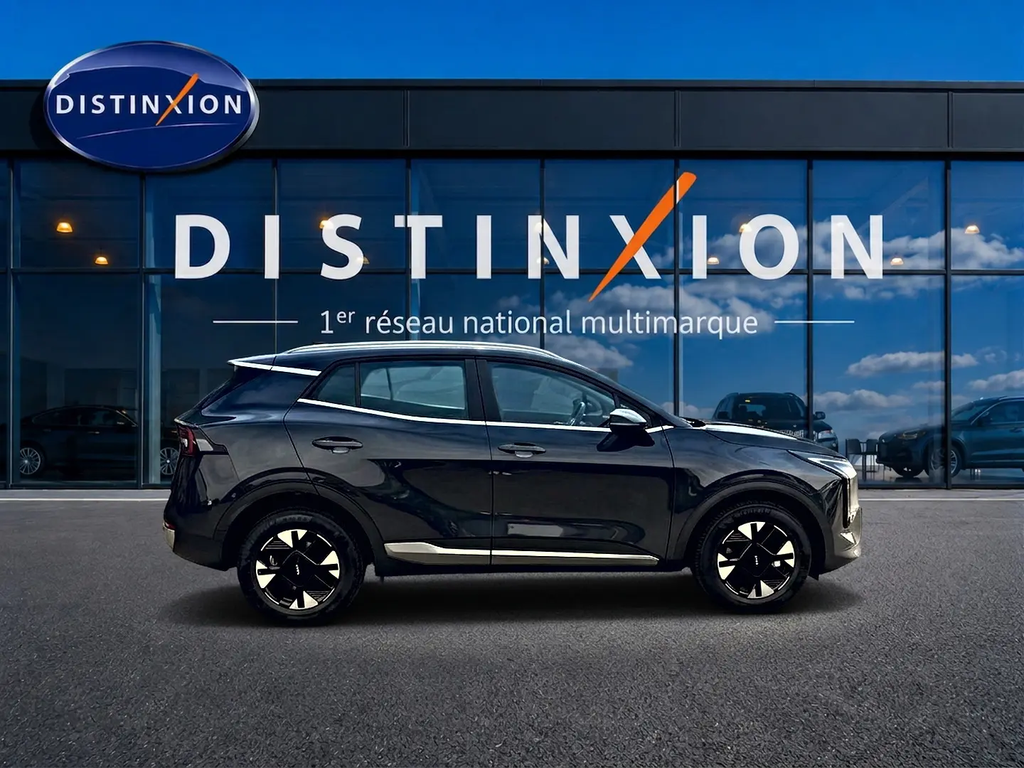 Vue latérale droite du KIA SPORTAGE 1.6 hybride 239 active gris eclipse avec jantes alu 17 pouces devant une vitrine Distinxion.