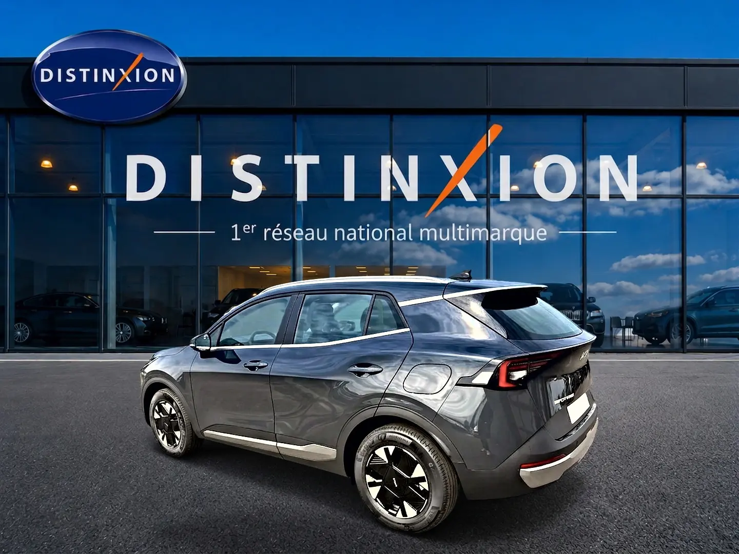 KIA Sportage 1.6 hybride gris eclipse vu en 3/4 arrière droit devant un showroom Distinxion.
