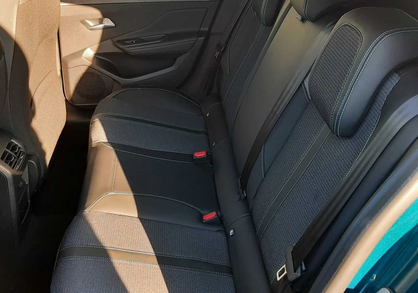 Vue latérale droite de la banquette arrière noire avec surpiqûres vertes du Peugeot 308 Bleu Obsession 2025.
