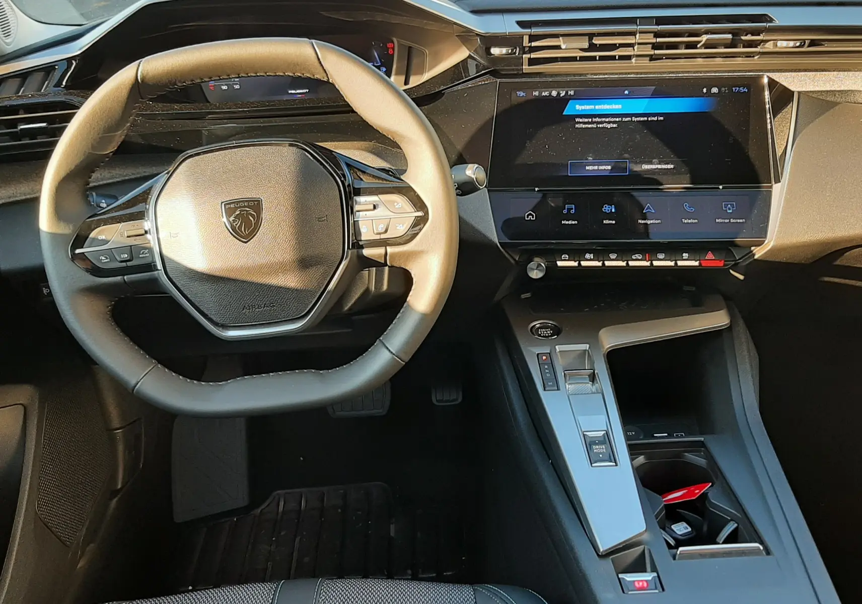 Vue intérieure avant du poste de conduite de la Peugeot 308 Bleu Obsession avec volant compact et écran tactile central.