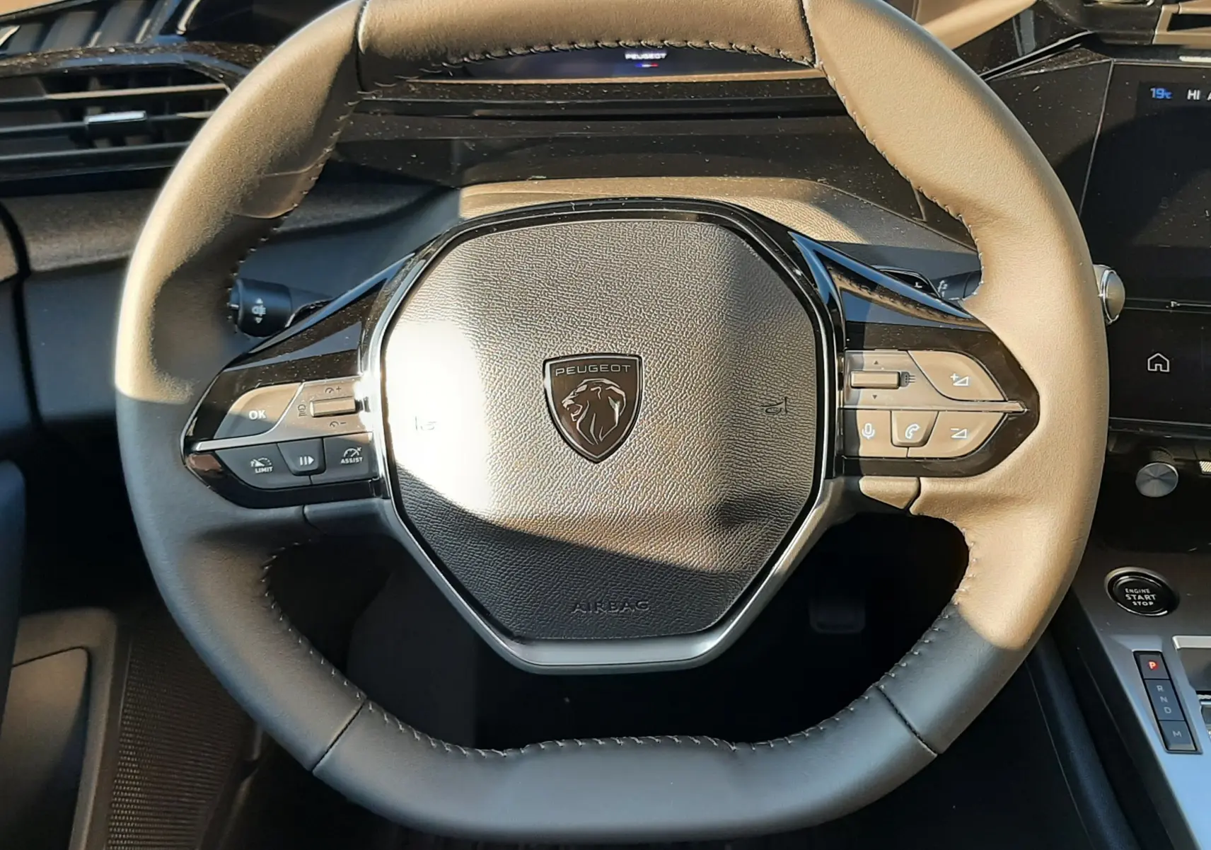 Vue rapprochée du volant cuir bicolore de la Peugeot 308 2025 avec commandes intégrées et logo lion central.