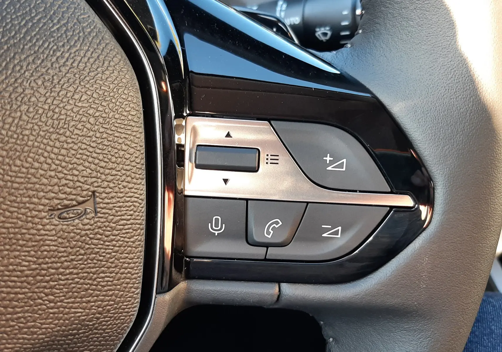 Gros plan sur les commandes du volant côté droit d'une Peugeot 308 Bleu Obsession 2025, avec boutons de volume et téléphone.