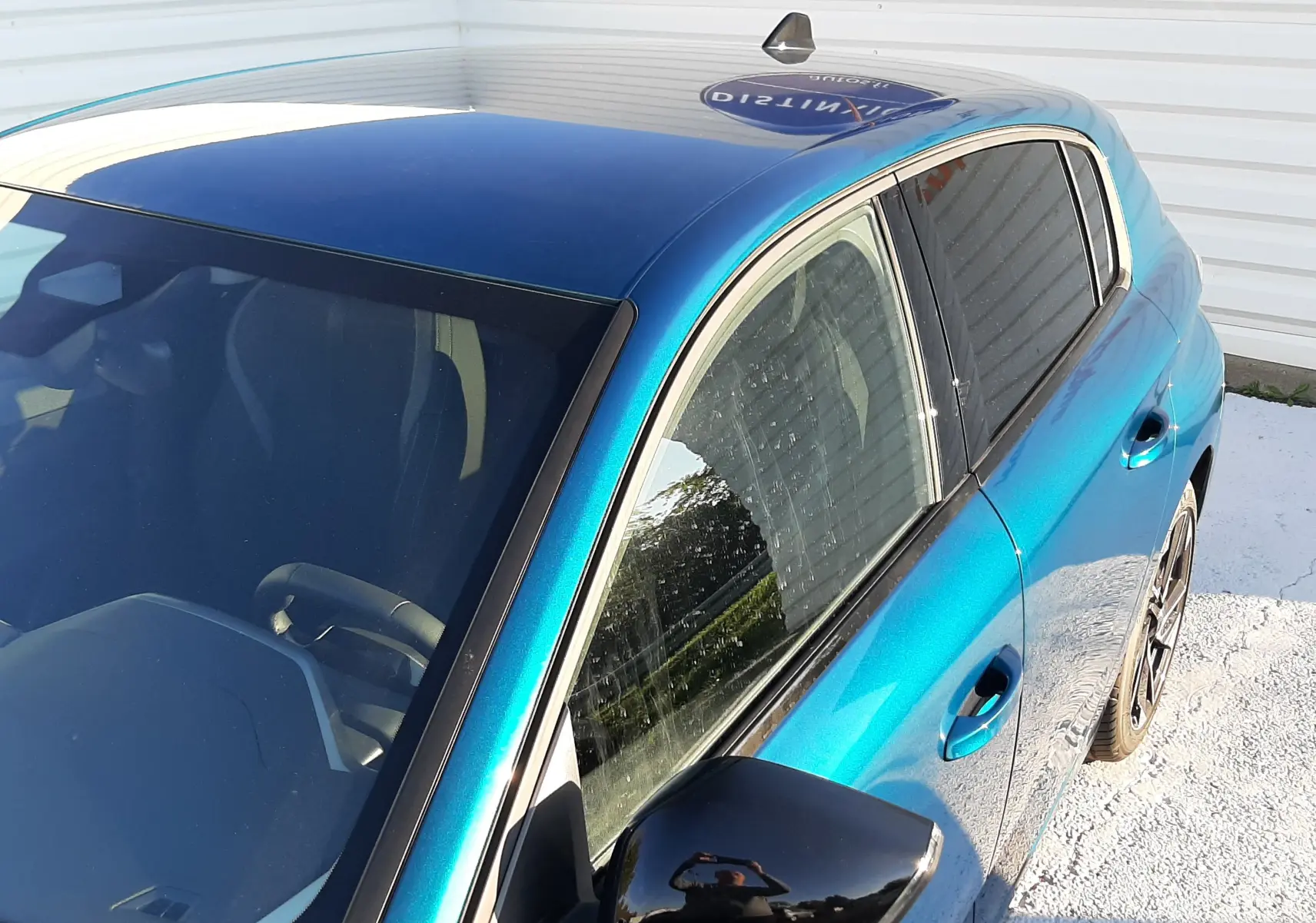 Vue plongeante côté droit sur la Peugeot 308 Bleu Obsession avec rétroviseur noir brillant et vitres teintées.