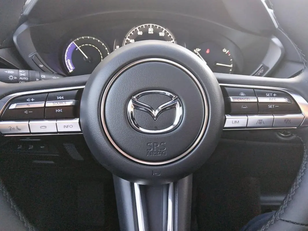 Vue rapprochée du volant noir de la Mazda MX-30 électrique 2021 avec commandes intégrées et logo central chromé.