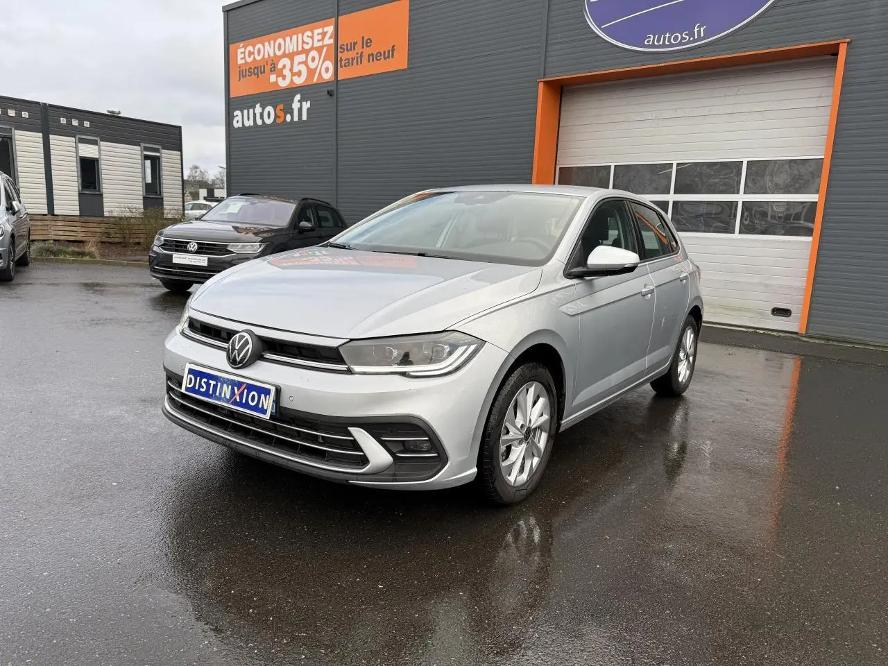 Volkswagen Polo 1.0 TSI Style argent métallisé vue 3/4 avant sur parking devant un garage autos.fr