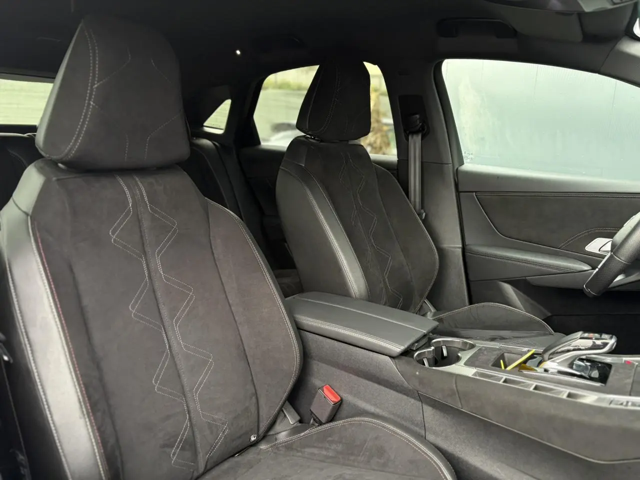 Vue intérieure côté avant droit du DS7 2024, sièges en Alcantara noir profond avec surpiqûres et console centrale élégante.