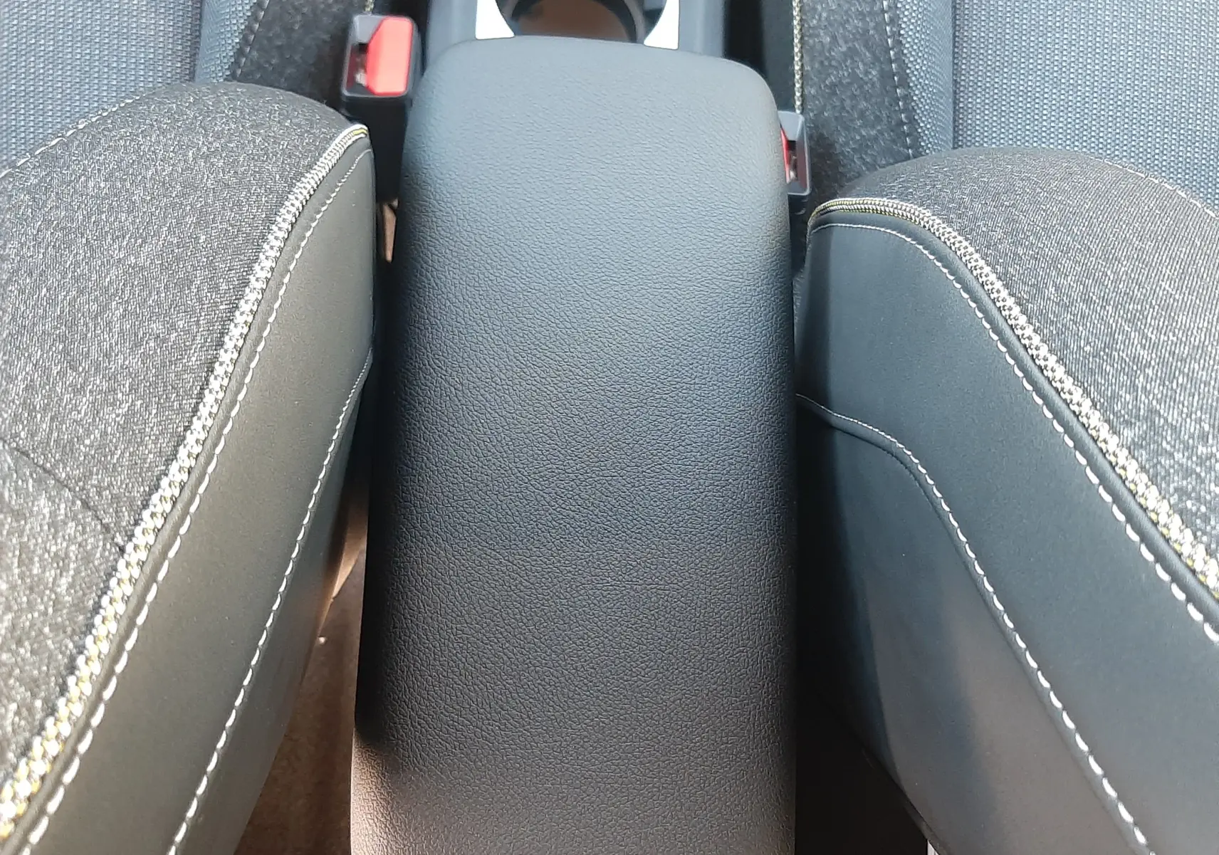 Vue plongeante sur l'accoudoir central en cuir noir et les sièges tissu gris du Renault Captur II Ph.2 2025.