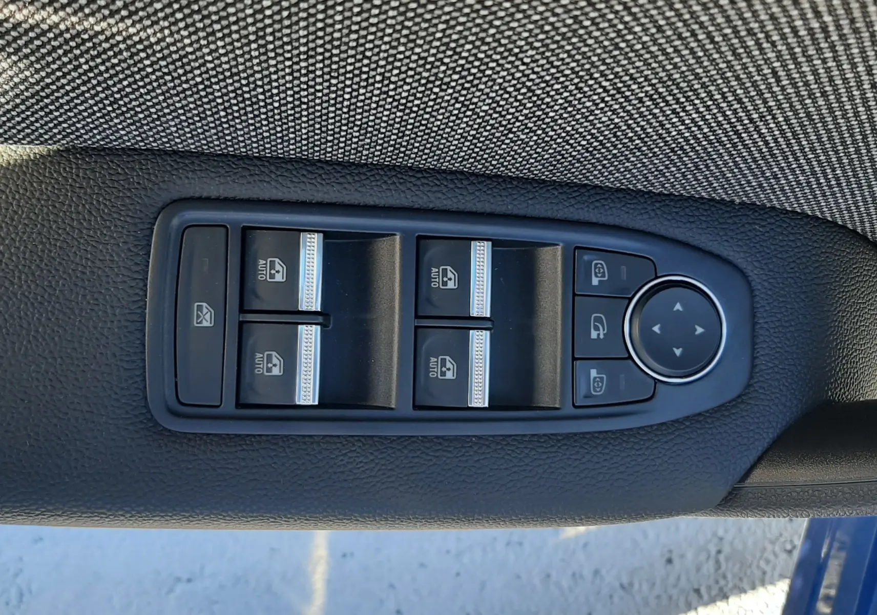 Panneau de commandes des vitres et rétroviseurs sur la porte côté gauche d'un Renault Captur bleu Iron 2025.