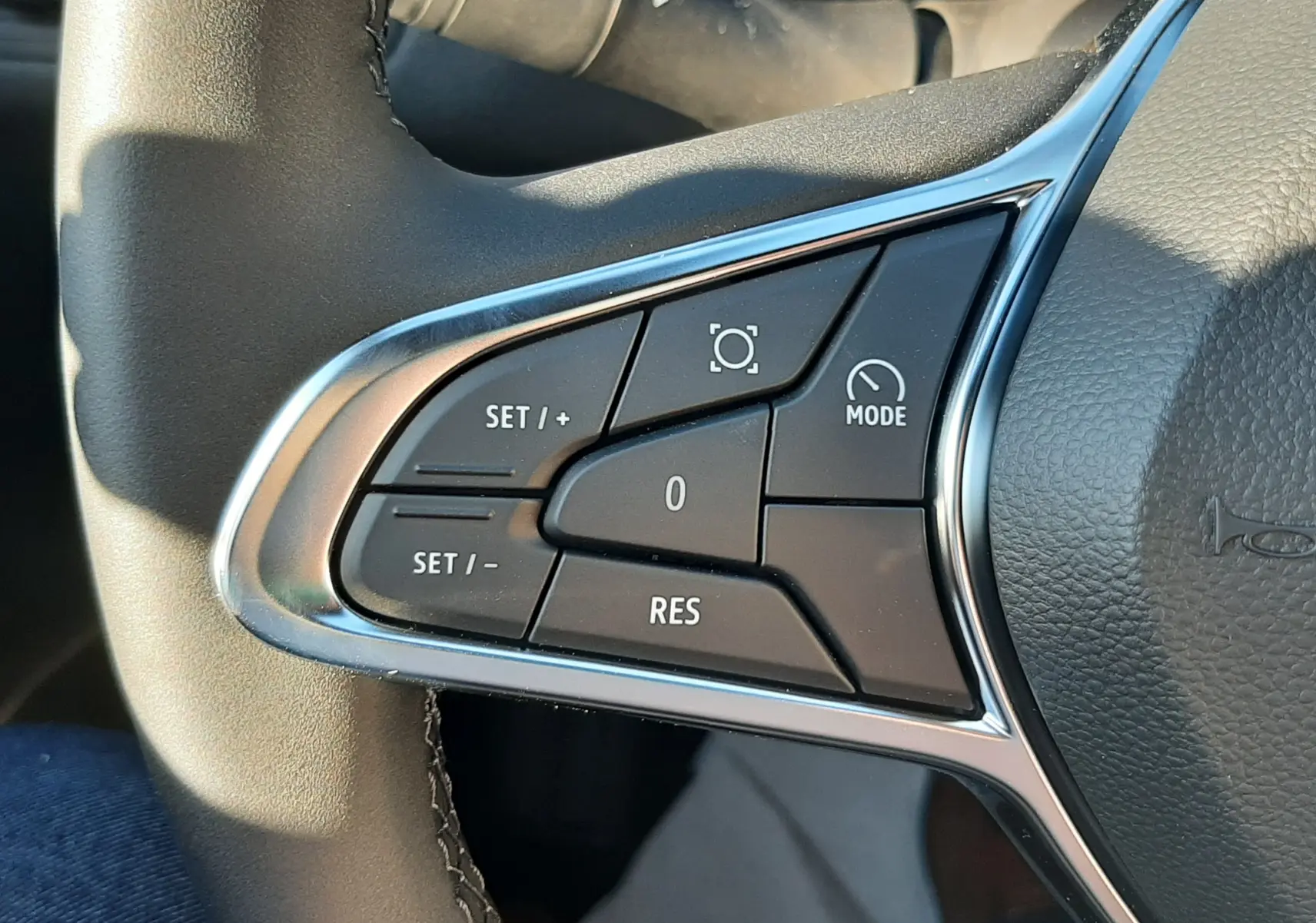 Gros plan sur les commandes de régulateur de vitesse au volant du Renault Captur II Ph.2, finition cuir noir.