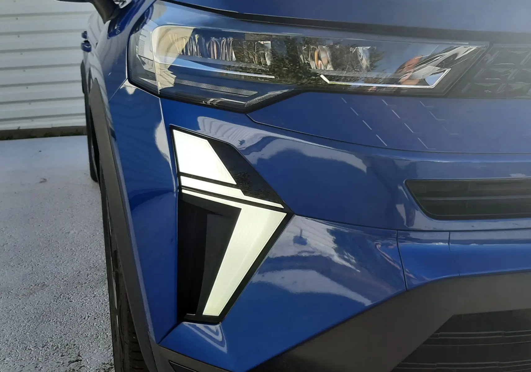 Gros plan sur l'avant droit du Renault Captur bleu Iron 2025, mettant en valeur ses feux LED au design angulaire.