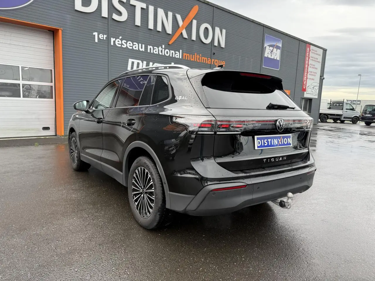 Volkswagen Tiguan noir grenadille métallisé vu en 3/4 arrière droit avec crochet d'attelage et jantes alliage 18 pouces.