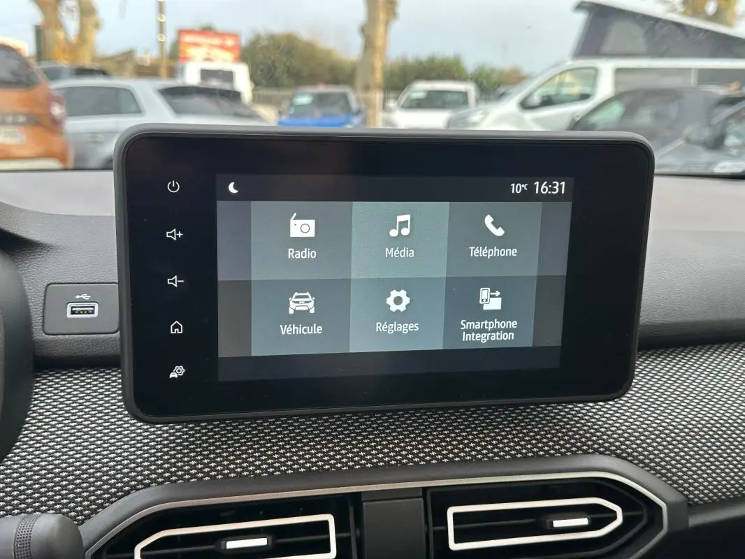 Écran tactile central du tableau de bord de la Dacia Sandero blanc, affichant le menu principal multimédia.