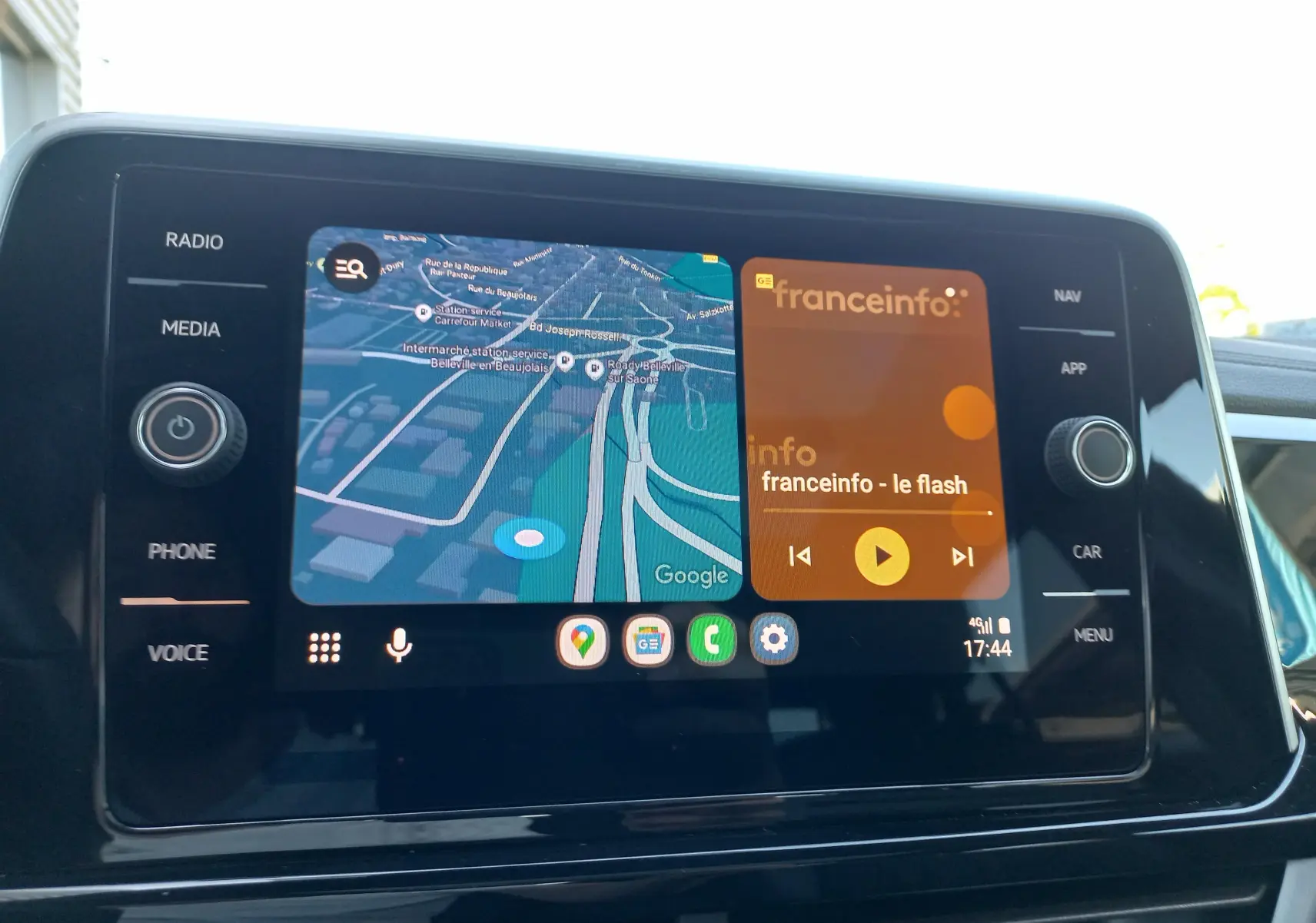 Écran central tactile du Volkswagen T-Roc 2025 affichant navigation et radio, avec commandes latérales visibles.